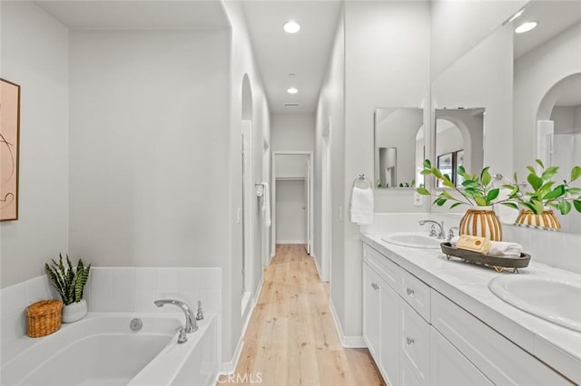 bathroom featuring hardwood / wood-style flooring, vanity, and a tub