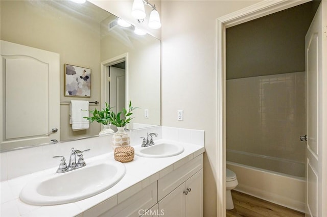 full bathroom with wood-type flooring, vanity, a notable chandelier,  shower combination, and toilet