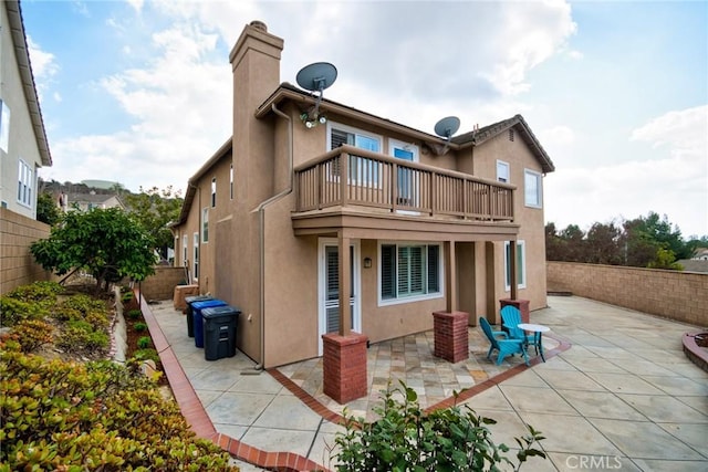 rear view of property featuring a balcony and a patio area