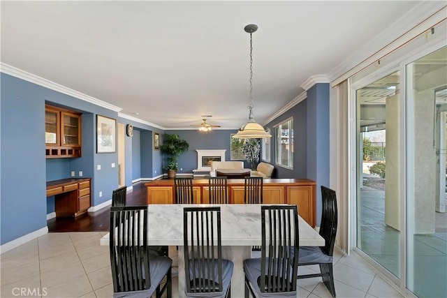 tiled dining room with crown molding, built in desk, and ceiling fan