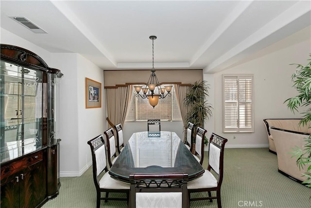 carpeted dining space with an inviting chandelier and a raised ceiling