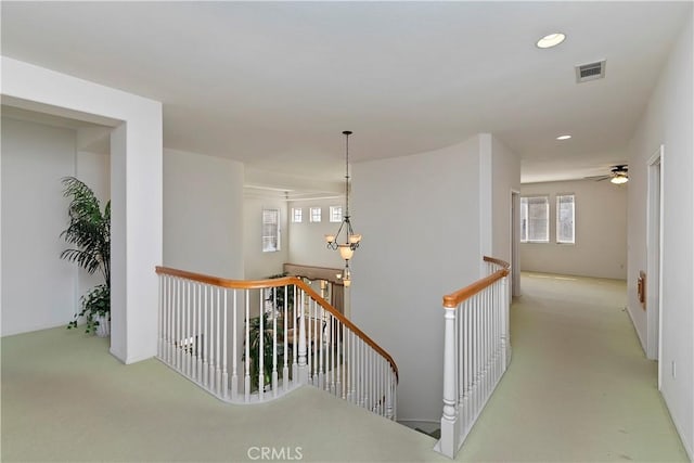 hallway with a chandelier and light carpet