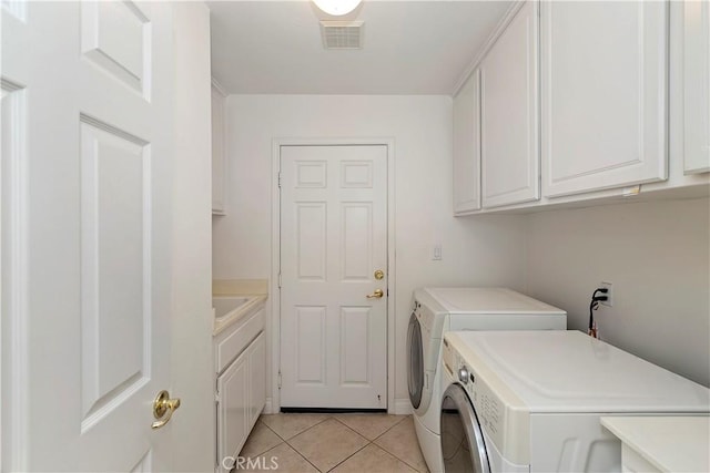 washroom featuring light tile patterned flooring, cabinets, and washer and clothes dryer