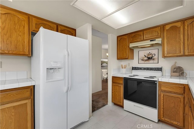 kitchen with electric stove, white refrigerator with ice dispenser, and tile countertops