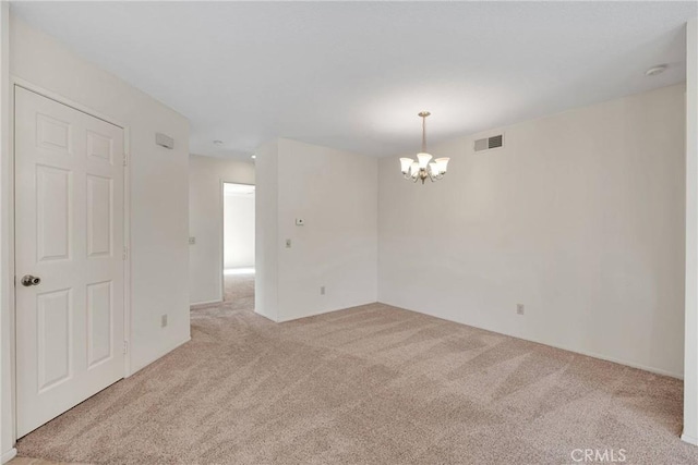 spare room with an inviting chandelier and light colored carpet