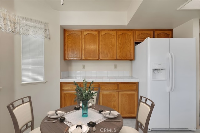 kitchen featuring tile countertops and white refrigerator with ice dispenser