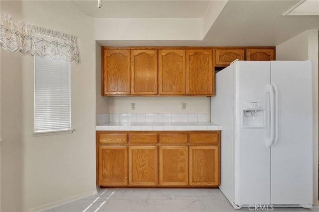 kitchen featuring tile counters and white refrigerator with ice dispenser