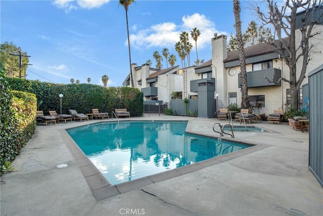 community pool with a residential view, fence, and a patio