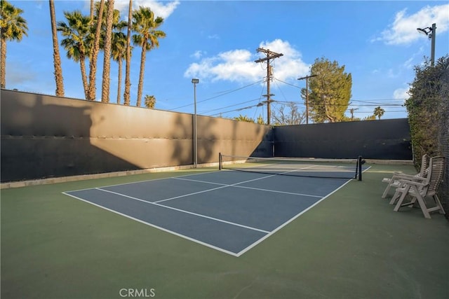 view of tennis court featuring community basketball court and fence