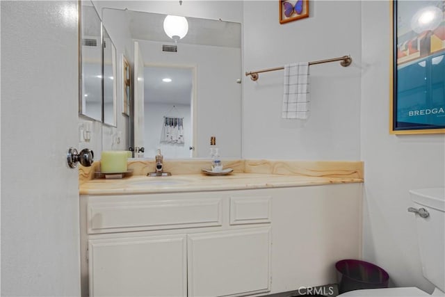 bathroom featuring toilet, visible vents, and vanity