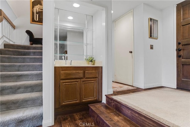 bar featuring indoor wet bar, dark wood finished floors, recessed lighting, stairway, and baseboards