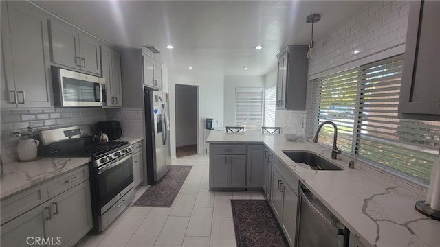 kitchen featuring appliances with stainless steel finishes, gray cabinets, a sink, and pendant lighting