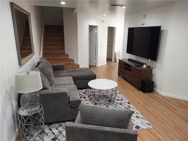 living room featuring recessed lighting, visible vents, light wood-style flooring, baseboards, and stairs