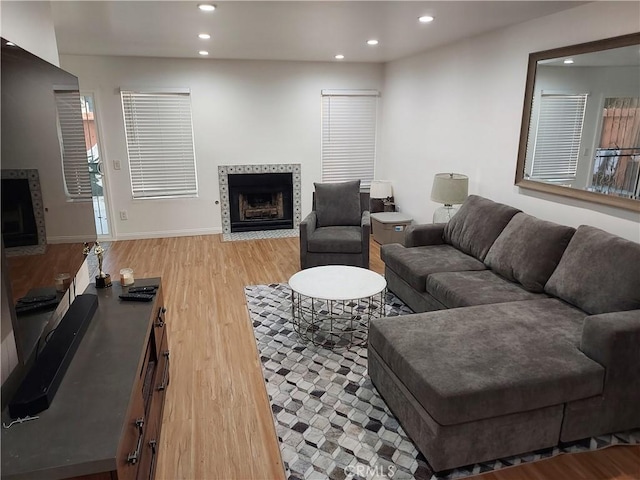 living room with baseboards, light wood-style floors, a fireplace, and recessed lighting