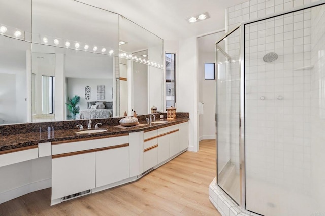 bathroom with hardwood / wood-style flooring, vanity, and an enclosed shower