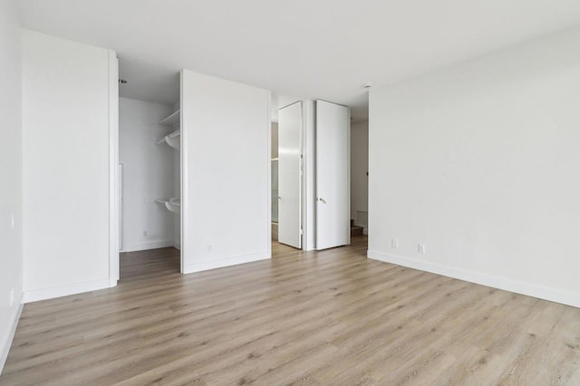 unfurnished bedroom with a walk in closet, light hardwood / wood-style floors, and ensuite bath