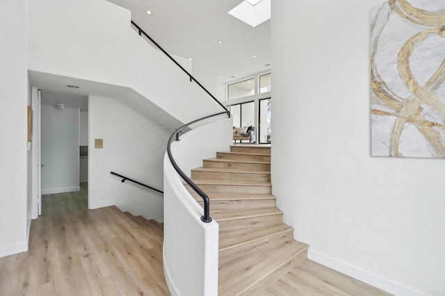 stairs featuring hardwood / wood-style floors and a skylight