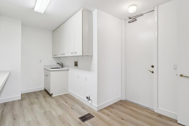 laundry room featuring washer hookup, sink, cabinets, and light wood-type flooring