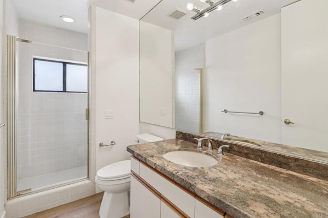 bathroom featuring vanity, toilet, a shower with shower door, and hardwood / wood-style floors