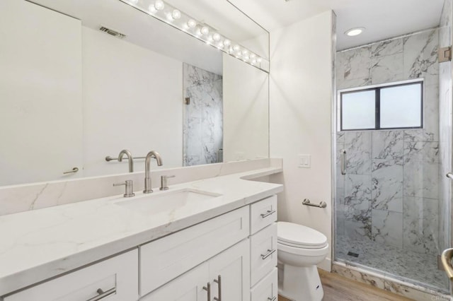 bathroom featuring toilet, hardwood / wood-style floors, vanity, and walk in shower