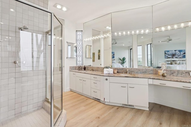 bathroom with walk in shower, ceiling fan, wood-type flooring, and vanity