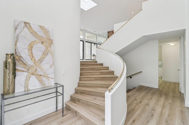 stairway with hardwood / wood-style floors and a skylight