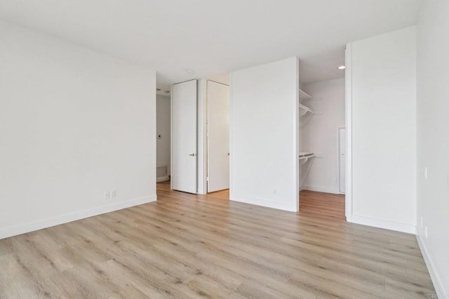 unfurnished bedroom featuring a walk in closet and light wood-type flooring