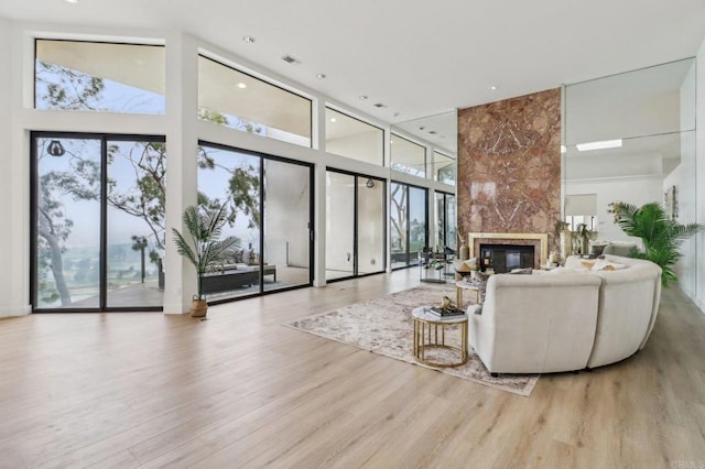 living room featuring a premium fireplace, light wood-type flooring, and a wealth of natural light