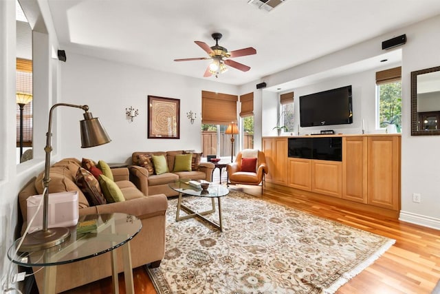 living area featuring light wood-type flooring, visible vents, ceiling fan, and baseboards