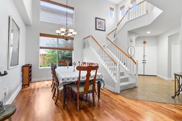 dining space featuring stairs, a notable chandelier, baseboards, and wood finished floors