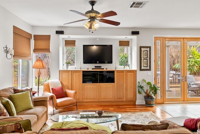 living room with light wood-style floors, french doors, visible vents, and ceiling fan