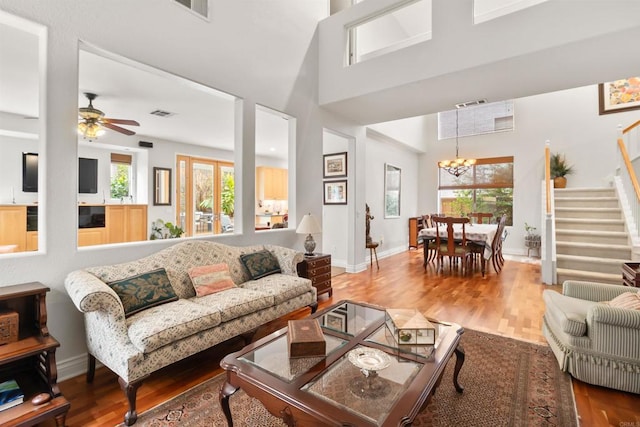 living area with baseboards, plenty of natural light, stairway, and wood finished floors