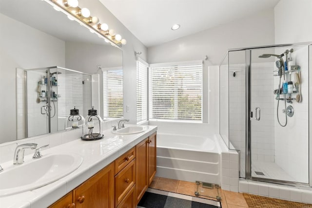 bathroom featuring lofted ceiling, a bath, a sink, and tile patterned floors