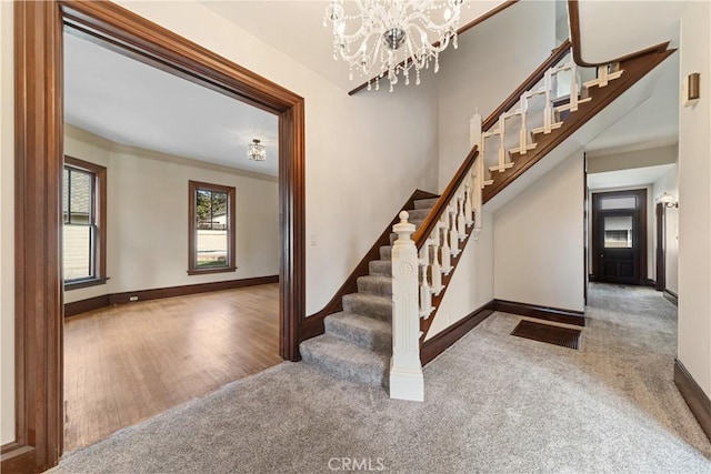 stairs with ornamental molding, carpet flooring, and a chandelier