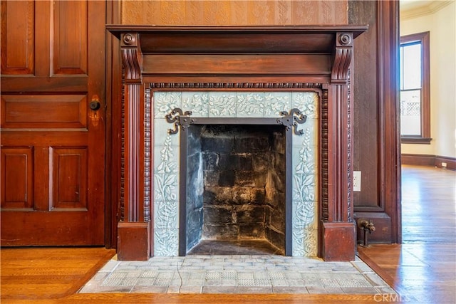 interior details featuring a tile fireplace, ornamental molding, and hardwood / wood-style floors