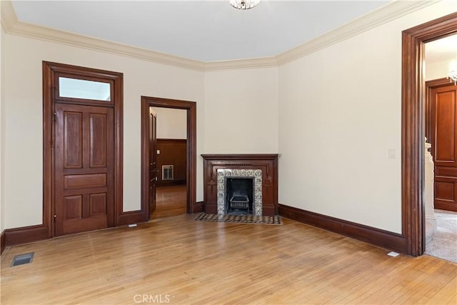 unfurnished living room with a tiled fireplace, crown molding, and light hardwood / wood-style floors