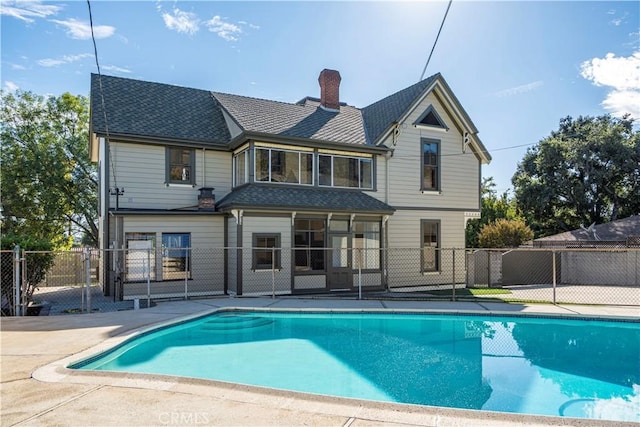 rear view of property with a fenced in pool