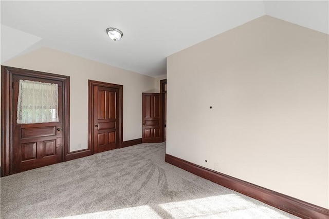 carpeted spare room with vaulted ceiling