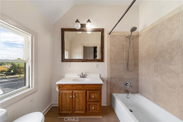 full bathroom featuring tiled shower / bath, lofted ceiling, hardwood / wood-style flooring, vanity, and toilet