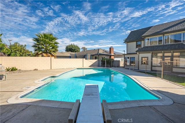 view of pool with a patio area and a diving board