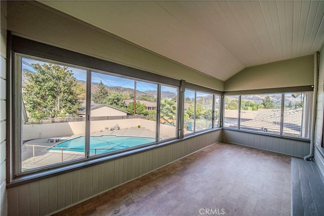 unfurnished sunroom featuring vaulted ceiling, a mountain view, and a wealth of natural light