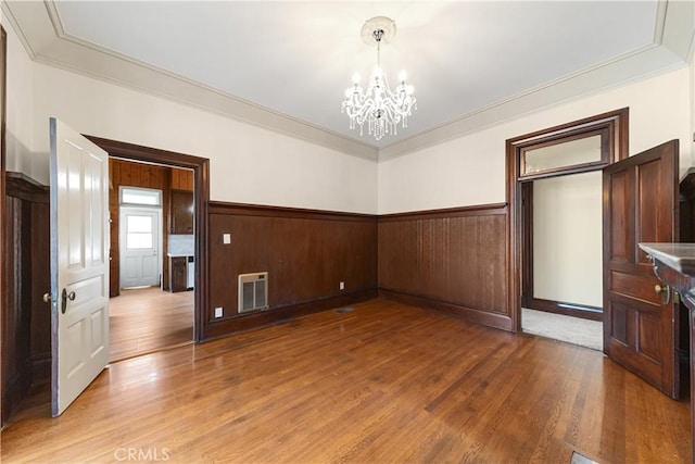 interior space with wood-type flooring, a notable chandelier, and crown molding