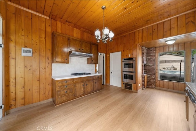 kitchen featuring appliances with stainless steel finishes, decorative light fixtures, a notable chandelier, wooden ceiling, and light hardwood / wood-style flooring