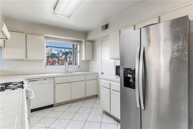 kitchen with sink, tile countertops, light tile patterned floors, white appliances, and white cabinets