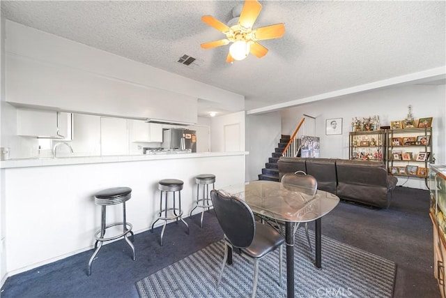 carpeted dining area with ceiling fan and a textured ceiling