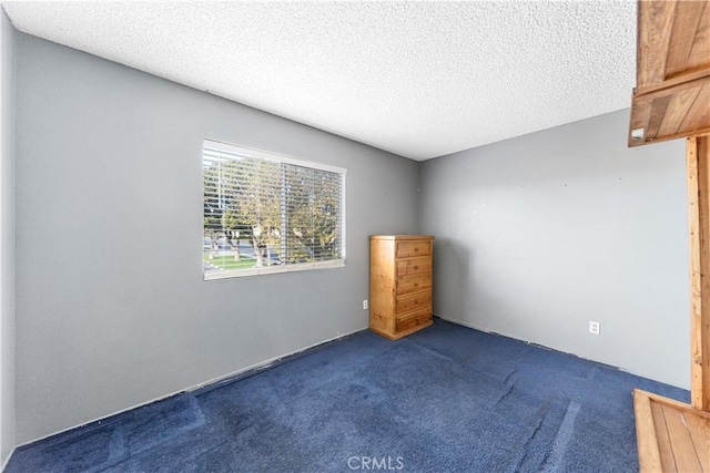 carpeted empty room featuring a textured ceiling