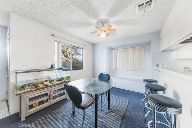 carpeted dining room featuring ceiling fan and a textured ceiling