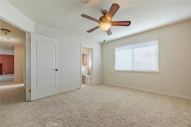 unfurnished bedroom featuring ceiling fan, light carpet, and ensuite bath