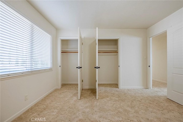 unfurnished bedroom with light carpet and two closets