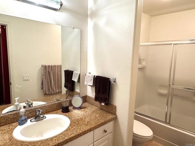 bathroom featuring toilet, combined bath / shower with glass door, an AC wall unit, and vanity